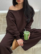 Seated close-up of the coffee brown off-shoulder sweatshirt with relaxed wide-leg pants