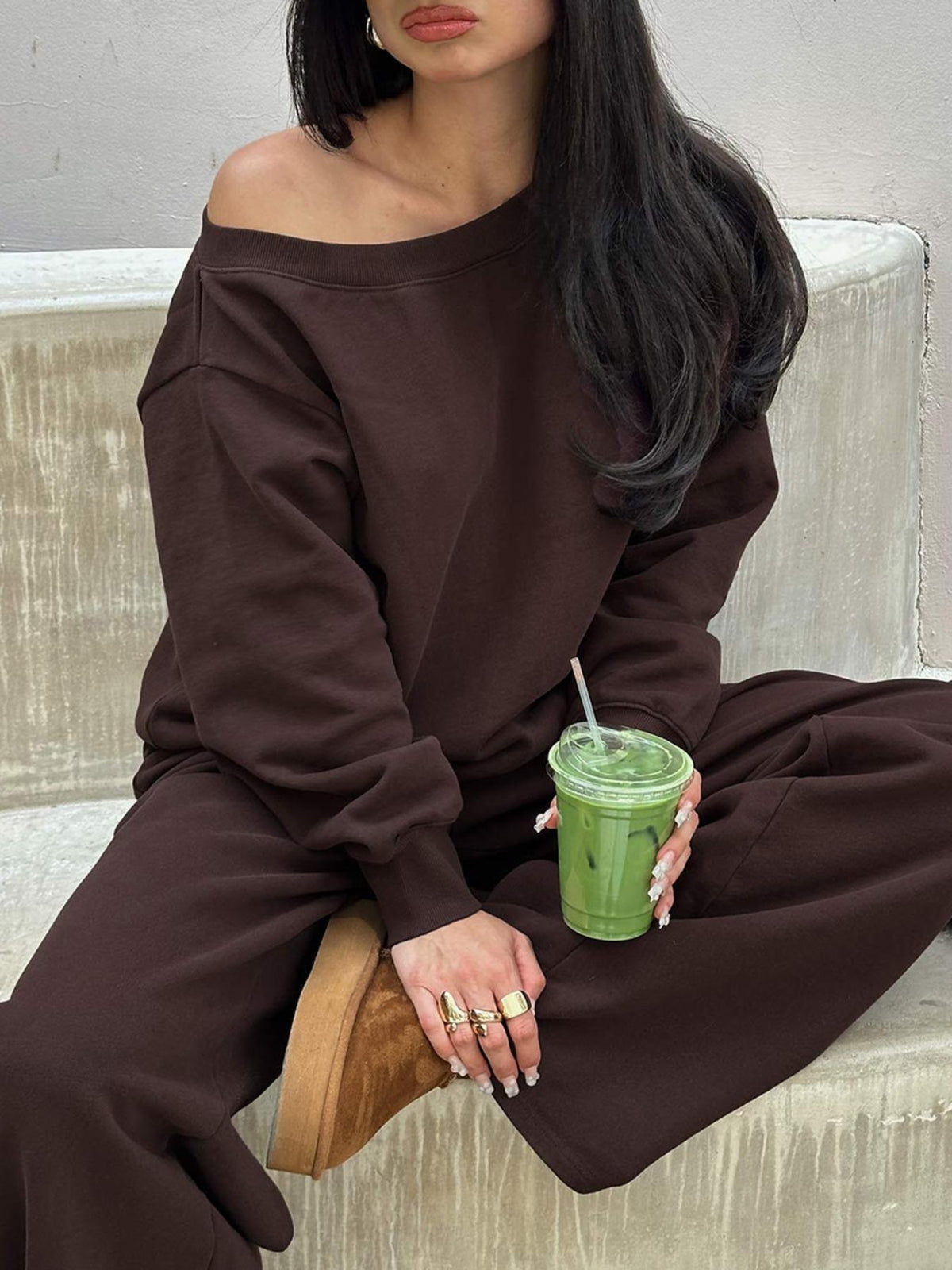 Seated close-up of the coffee brown off-shoulder sweatshirt with relaxed wide-leg pants