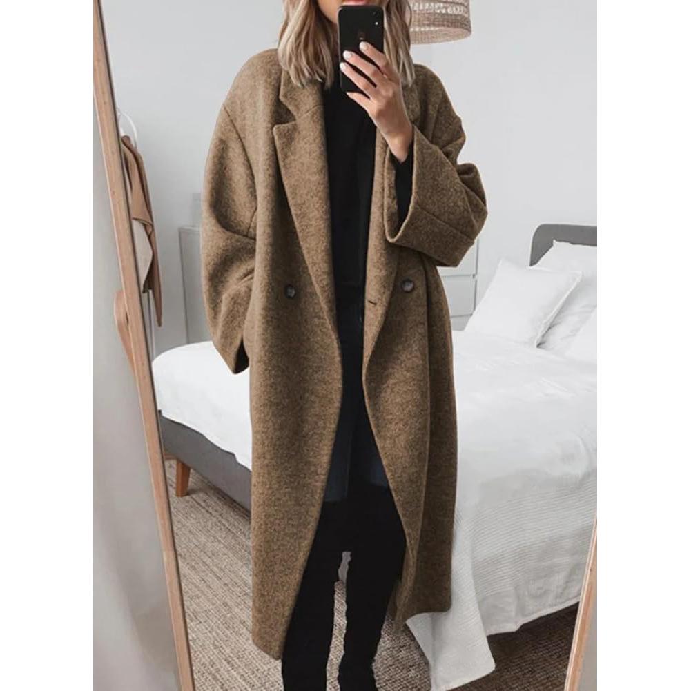 Brown long wool coat worn over an all-black outfit in a bright bedroom