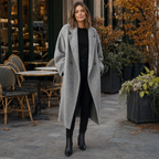 Woman in a light grey long wool coat in front of a cafe terrace
